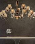 A table with a glass of wine and a Lorenzon Divina Chandelier emanating timeless elegance through its Italian craftsmanship.