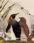 Maleras Crystal Sculpture King Penguin With Baby on wooden surface with flowers in back ground for modern interiors available at Spacio India from the Sculptures and Art Objects Collection.