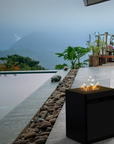Planika's Square Gas fireplace in an outdoor setting beside a swimming pool in a hill home.