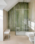 Modern bathroom with a glass shower enclosure and bamboo-themed wall.