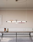 A modern dining room with a large Italamp Axi table and chairs illuminated by a stylish Italamp chandelier.