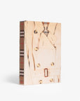 Linen slip case. Burberry coffee table book by Assouline, celebrating 165 years of British style, iconic trench coats, and timeless luxury through stunning illustrations and stories.