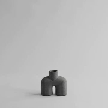 A small ceramic vase, the 101Cph Cobra Uno Mini Dark Grey 211032 by 101 Copenhagen, sitting on a white surface.