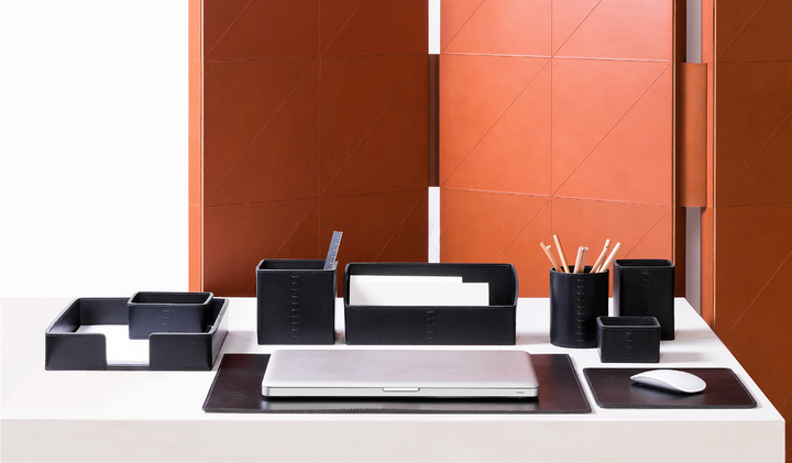 Black leather desk set with organisers on white table and orange leather panel backdrop