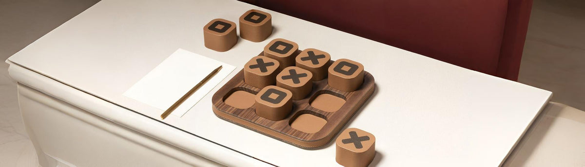 A designer tic tac toe set in wood and leather styled on a table. 