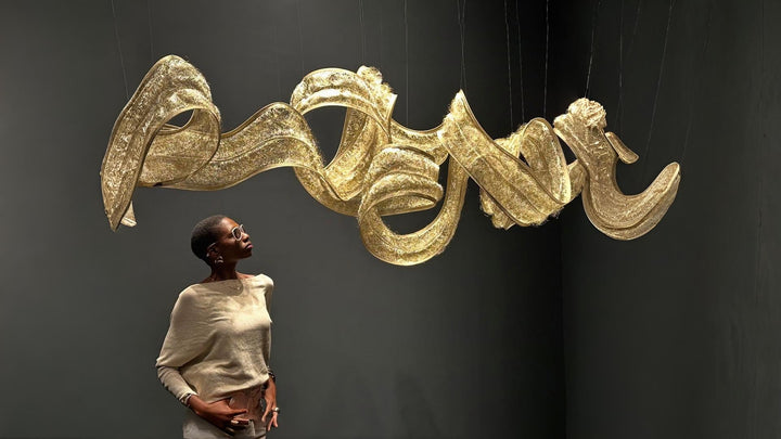 Terzani Metal fabric light sculpture in gold finish installed from the ceiling and a lady admiring the light. 