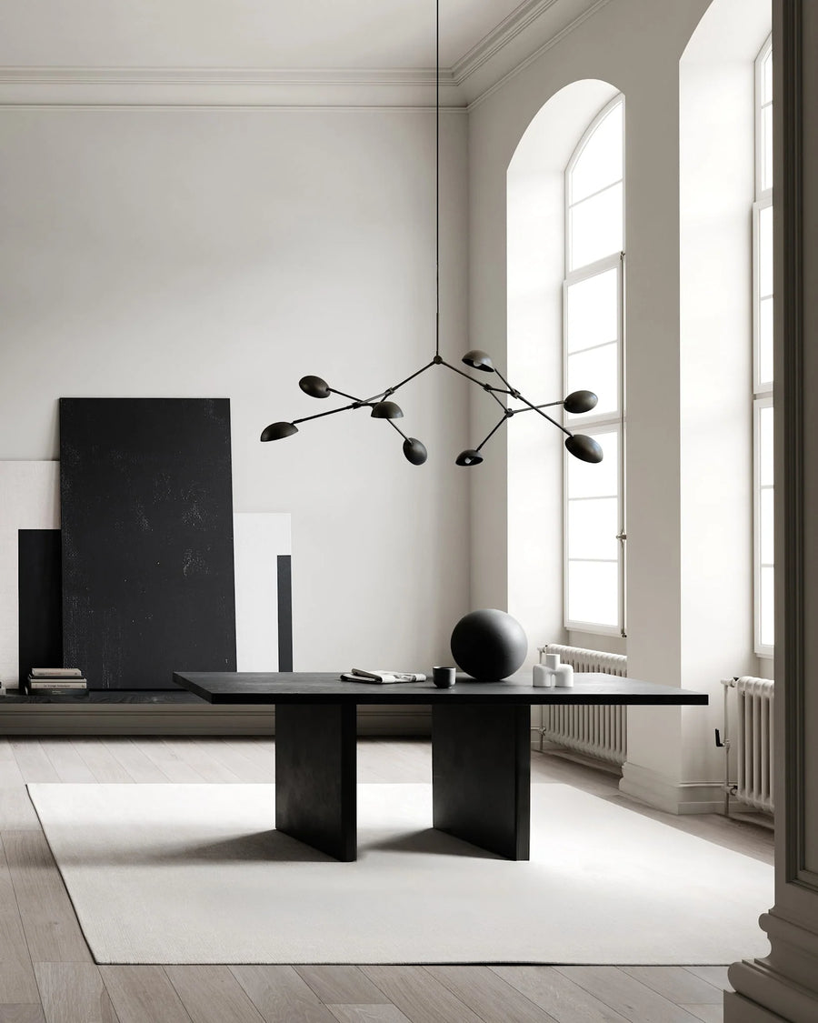A Scandinavian theme dining room styled with wall art, sculptural vase, wall art and a minimal design chandelier. 