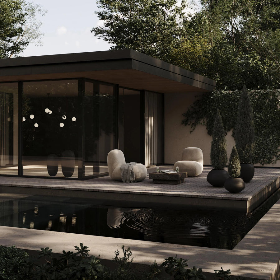Modern outdoor pavilion with seating area by a pond, surrounded by trees.