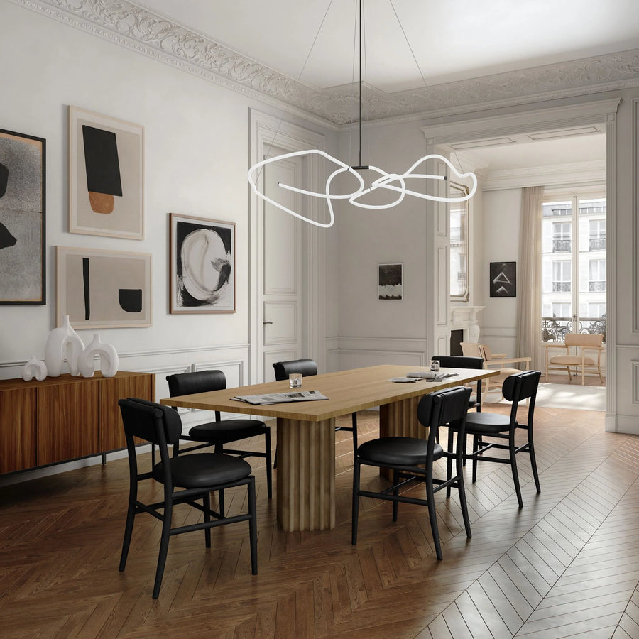 Modern dining room with wooden table and black chairs, featuring a stylish chandelier.