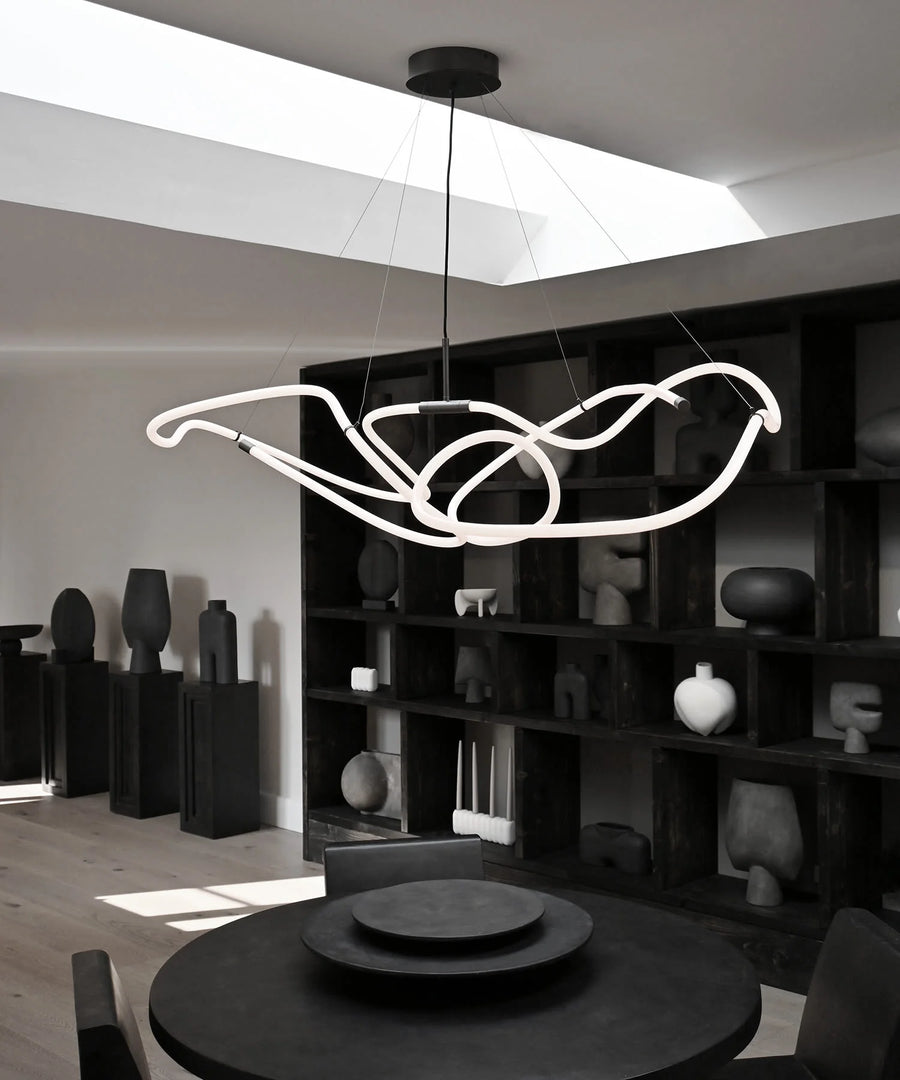 Modern chandelier hanging in a stylish room with bookshelves and decor.