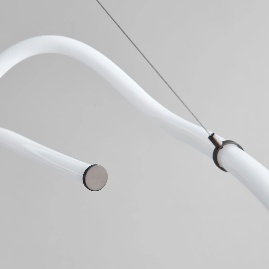 Close-up of a modern ceiling light fixture with white arm and metallic base.