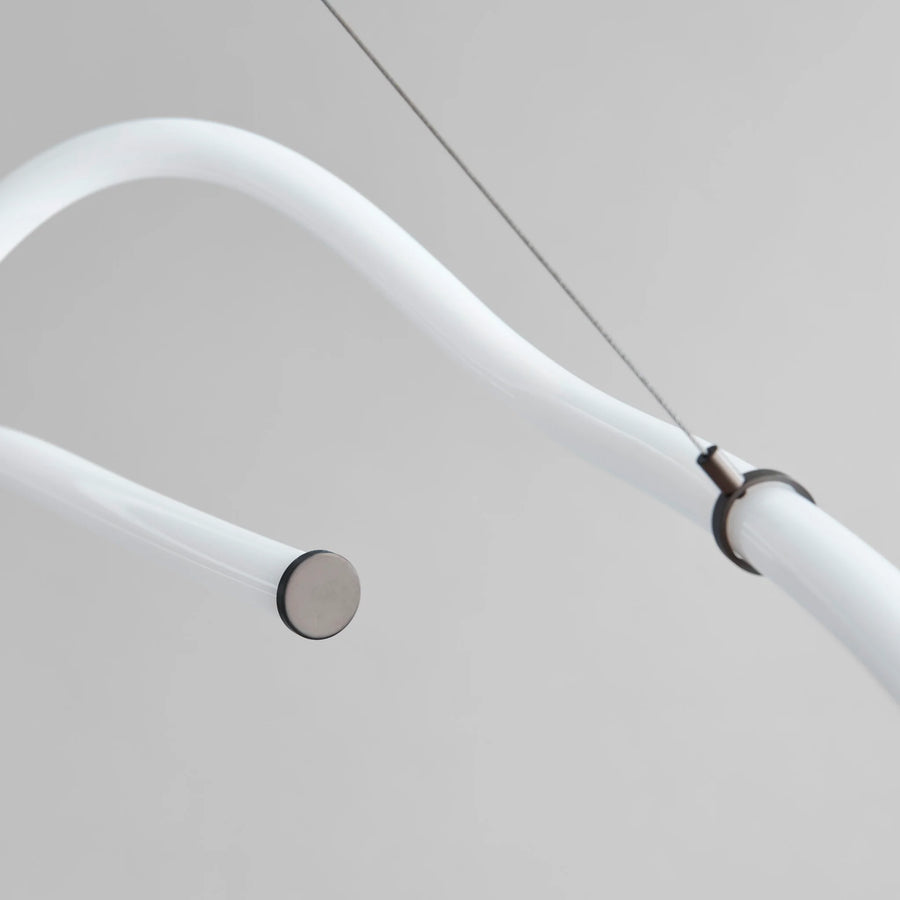 Close-up of a modern ceiling light fixture with white arm and metallic base.
