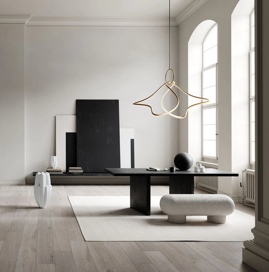 Modern interior with a black desk, white vase, and gold pendant light.