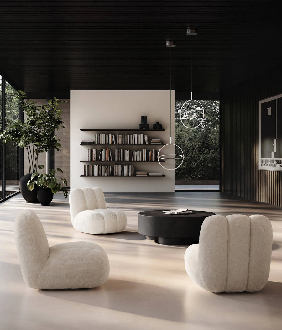 Modern Japandi theme living room with white armchairs, a round black coffee table, and bookshelves.