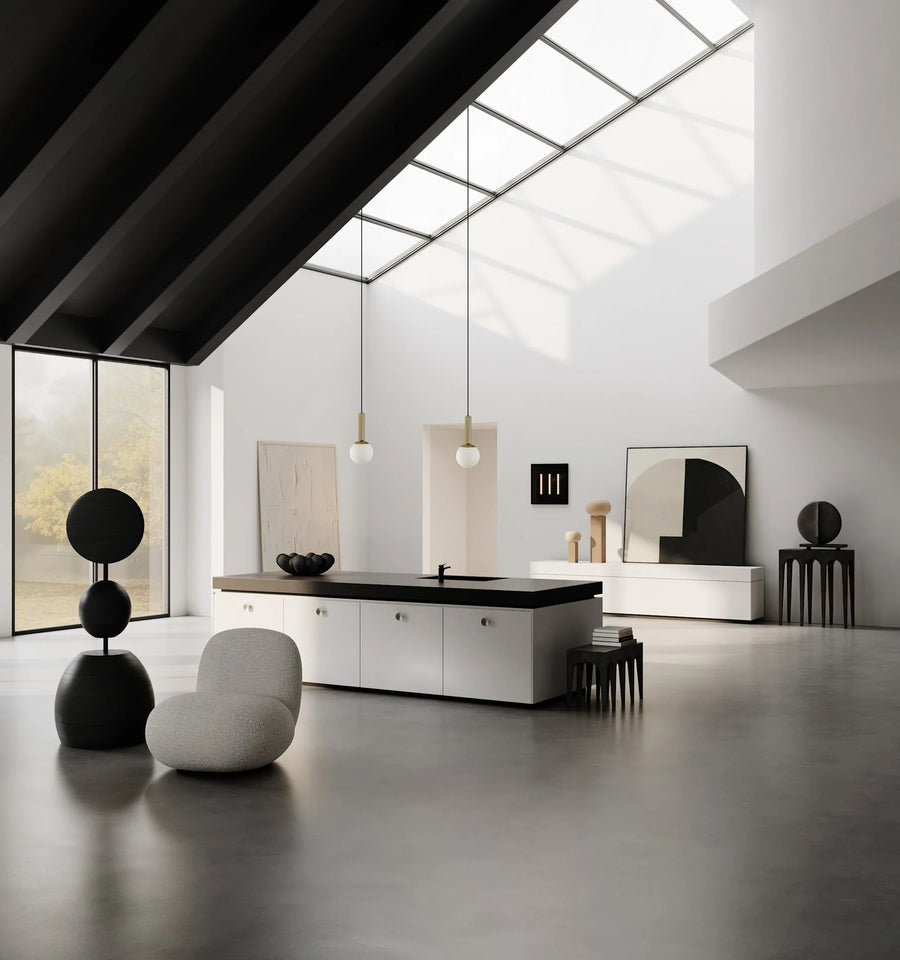 Modern kitchen with black countertops and white cabinetry, featuring a skylight.