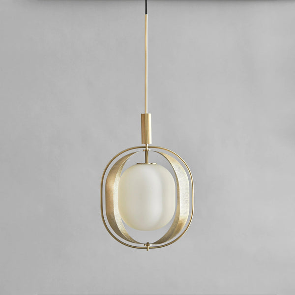 Modern pendant light with brass fixture and white glass shade on a gray background