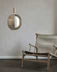 Modern Scandinavian chair with a hanging lamp against a plain wall