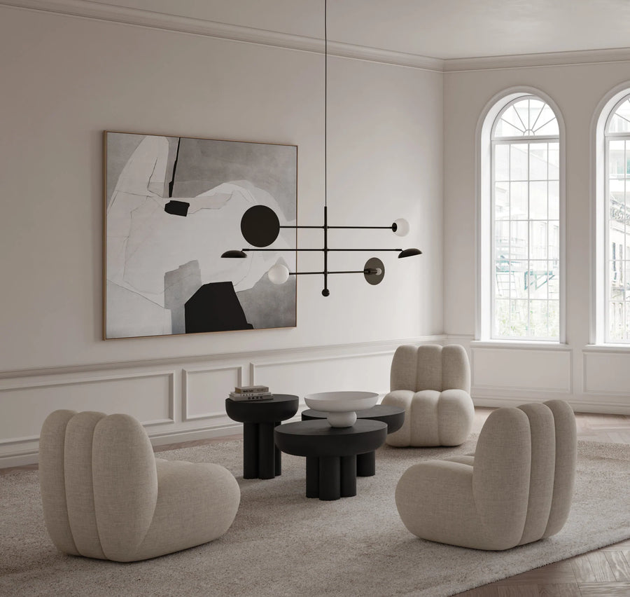 Modern living room with beige chairs, black coffee table, and abstract art on the wall.
