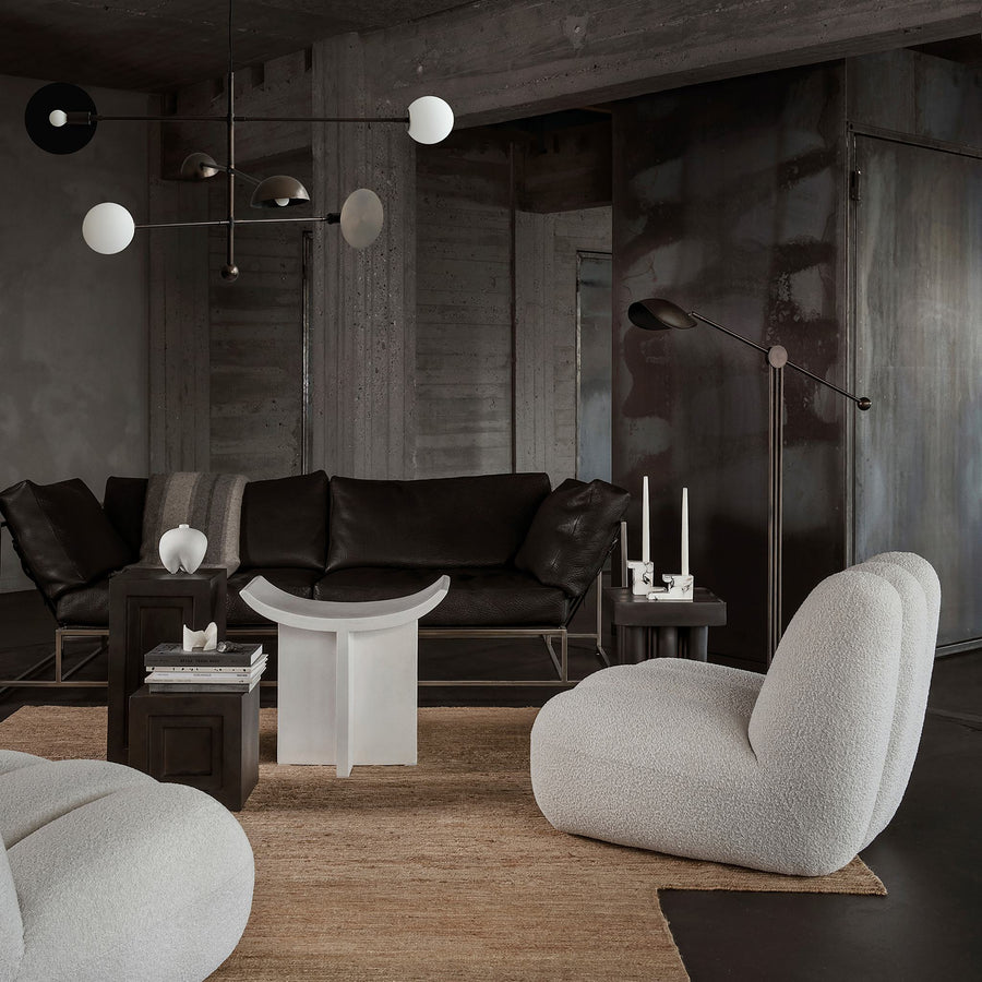 Modern living room with dark leather sofa, gray armchair, and minimal decor.