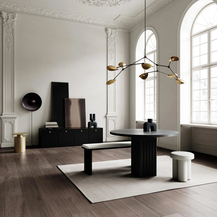 Modern interior design with a black round table, white bench, and decorative light fixture.