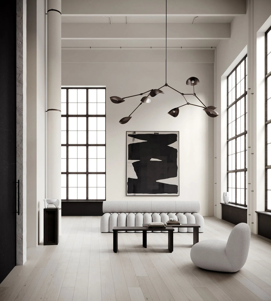 Modern living room with white walls, large windows, and minimal furniture.