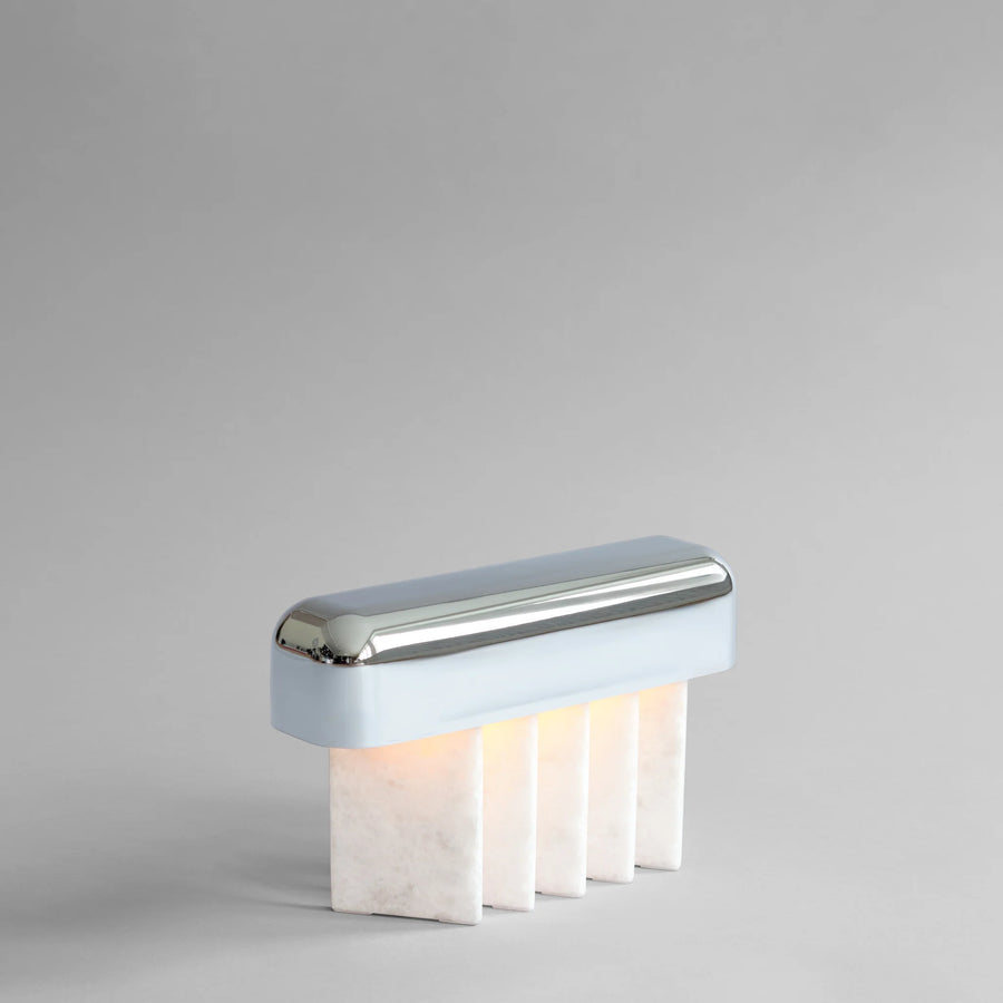 Modern portable table lamp with white base and chrome top on a gray background