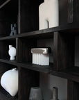 Dark wooden shelves with various white ceramic vases and objects against a black background