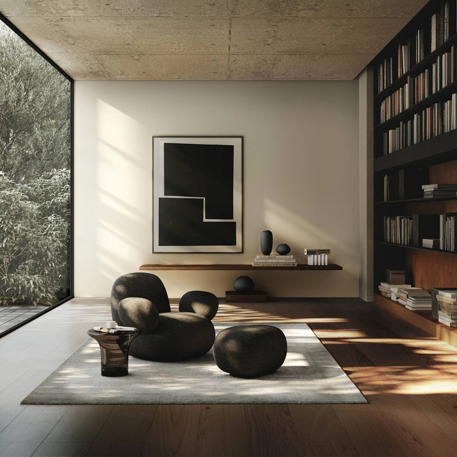 Modern living room with black chairs, a rug, and a bookshelf.