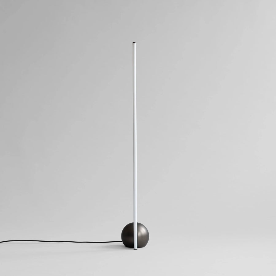 Modern floor lamp with a black base and white cylindrical shade on a light gray background
