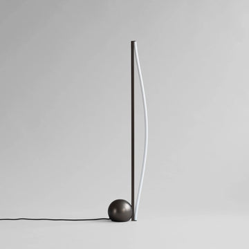 Minimalist floor lamp with a spherical base on a plain background