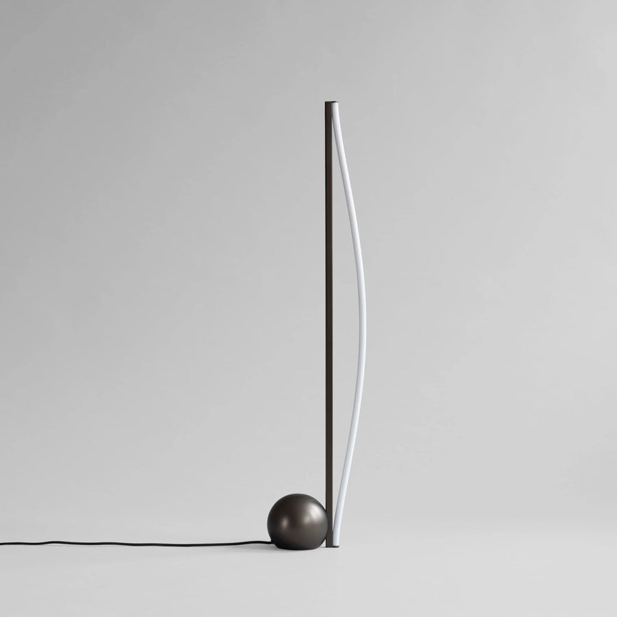 Minimalist floor lamp with a spherical base on a plain background