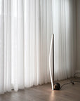 Modern floor lamp against a white curtain backdrop