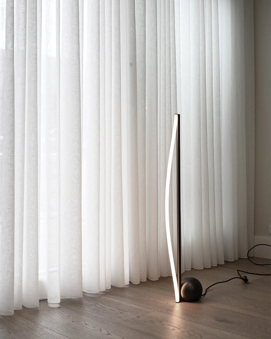 Modern floor lamp against a white curtain backdrop