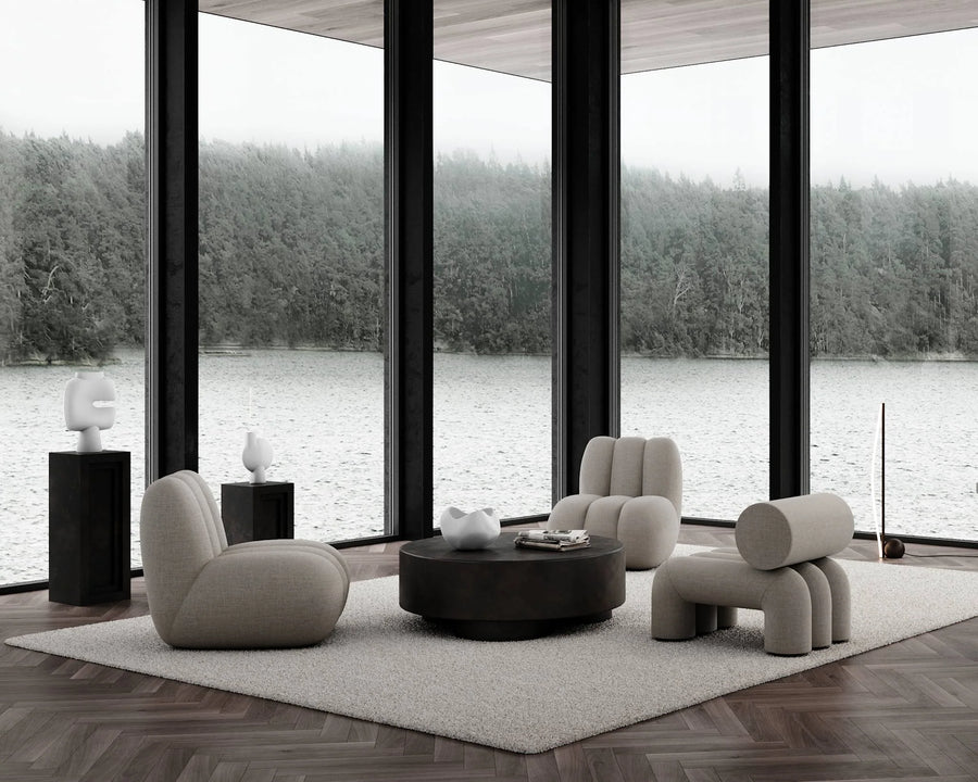 Modern living room with gray furniture and large windows overlooking a lake.
