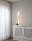 Modern floor lamp on a white radiator with white curtains in the background