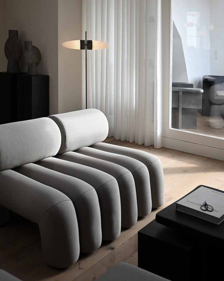 Modern living room with a unique gray sofa and a lamp.