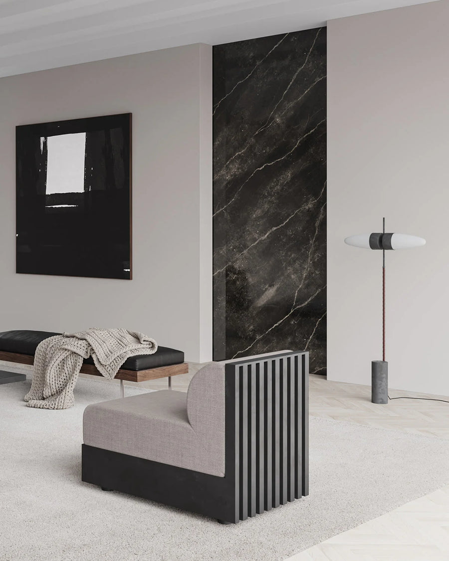 Modern interior with a gray sofa, black marble wall, and abstract art.