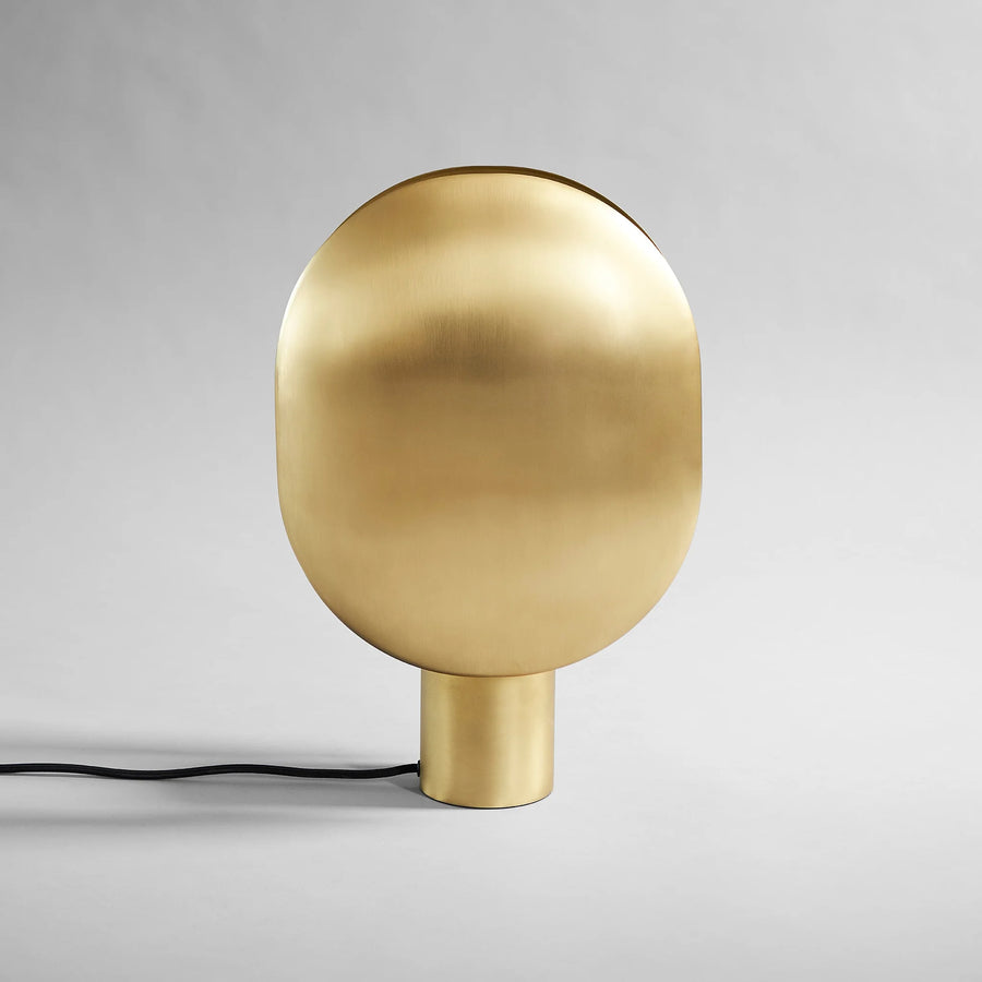 Brass table lamp on a gray background from 101 Copenhagen available at Spacio retail stores in Mumbai & Kolkata. 