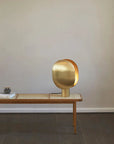 Brass table lamp on a wooden table against a plain wall