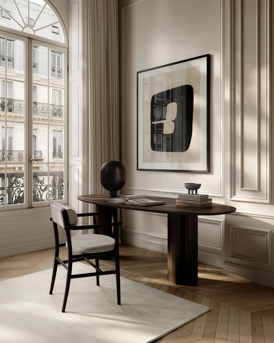 Modern home office setup with a desk, chair, and framed artwork on a wall.