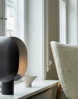 Modern black and gold spherical lamp on a windowsill with a neutral background