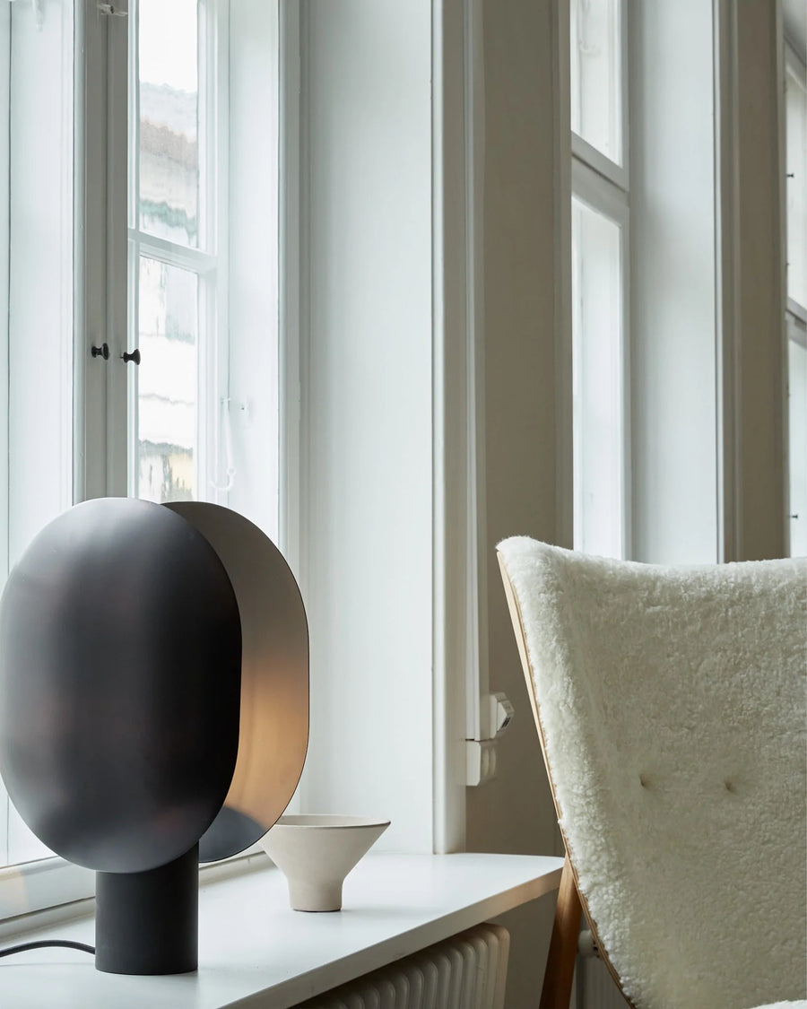 Modern black and gold spherical lamp on a windowsill with a neutral background