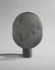 Dark gray concrete lamp on a light gray background from 101 Copenhagen available at Spacio retail stores in Mumbai & Kolkata.