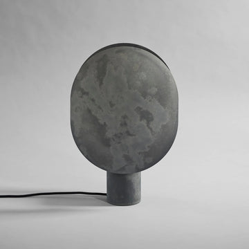 Dark gray concrete lamp on a light gray background from 101 Copenhagen available at Spacio retail stores in Mumbai & Kolkata.