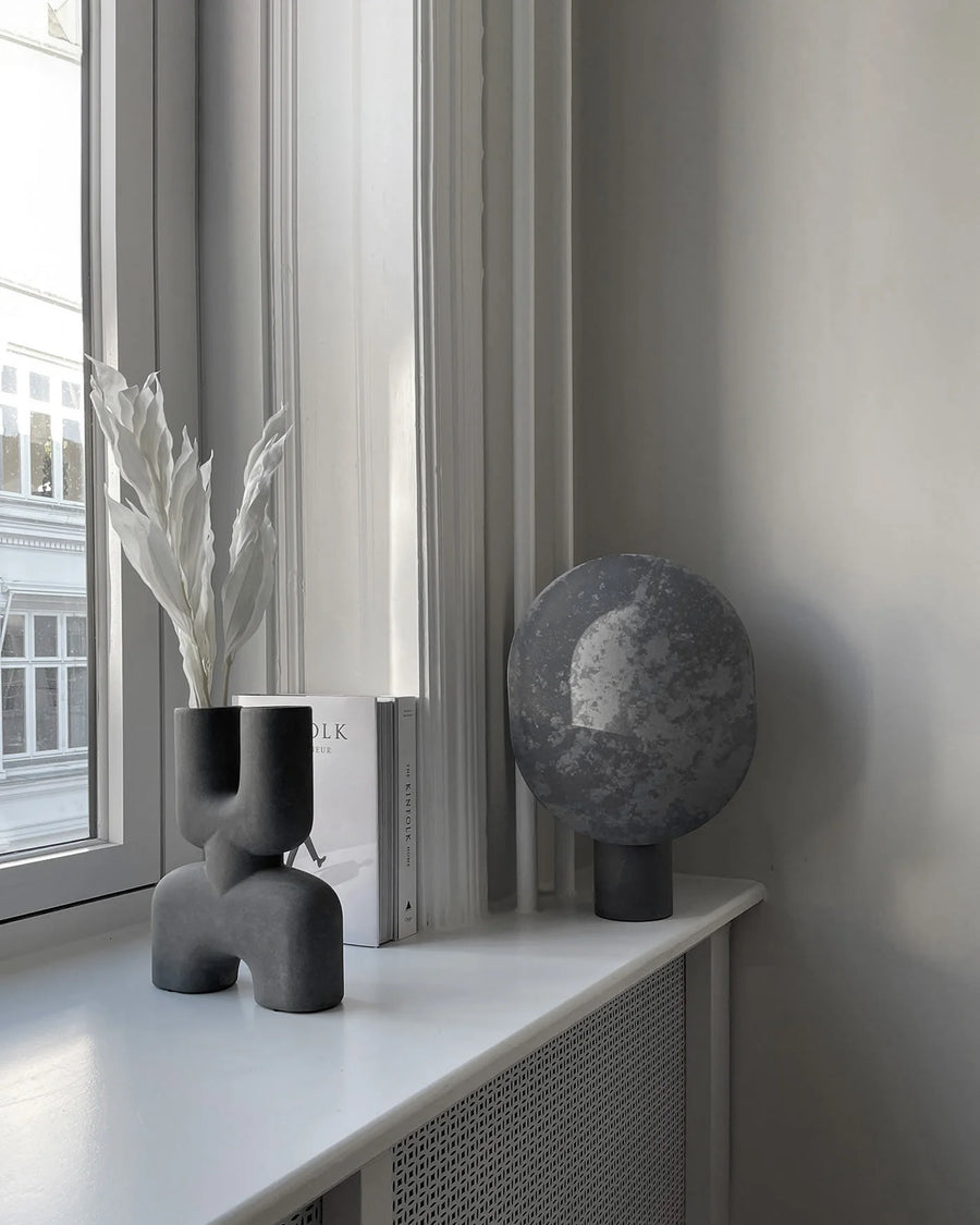 Gray decorative objects on a windowsill with a view of a building outside.