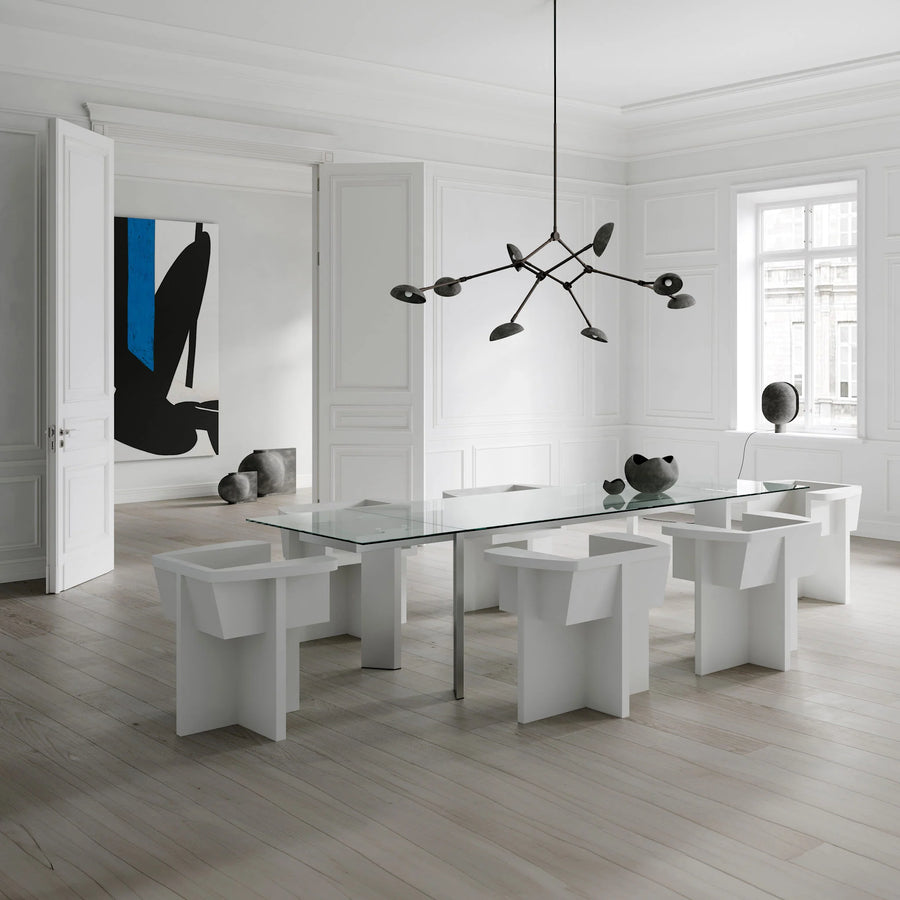 Modern dining room with a glass table and white chairs in a minimalistic setting.