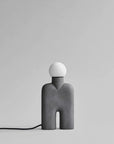 Modern & minimal table lamp with a gray base and white bulb on a light gray background from 101 Copenhagen available at Spacio retail stores in Mumbai & Kolkata. 