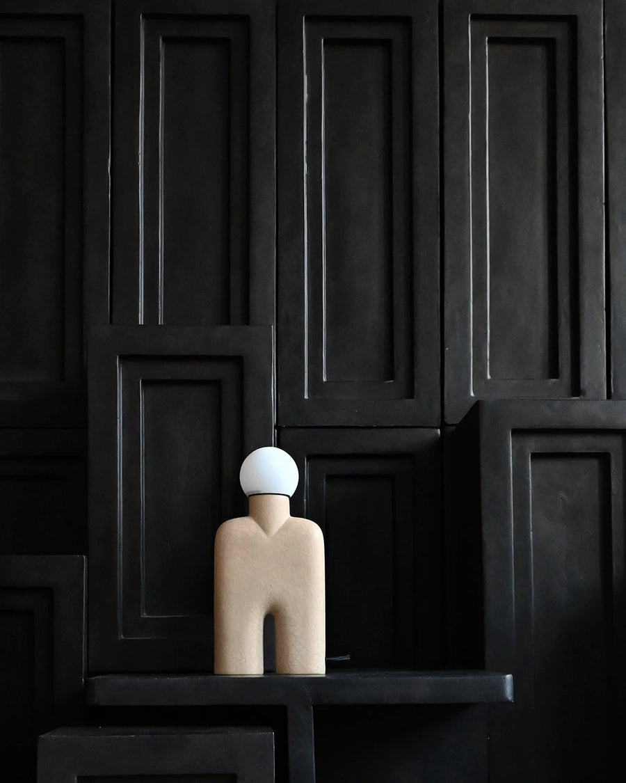 Decorative sculptural table lamp against a dark panelled wall