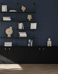 Black shelving unit with decorative items against a dark blue wall