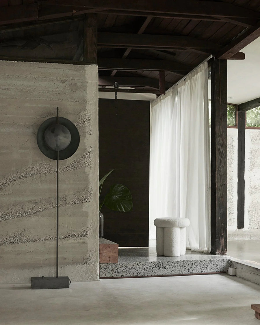 Modern interior with concrete wall, floor lamp, and white curtain.